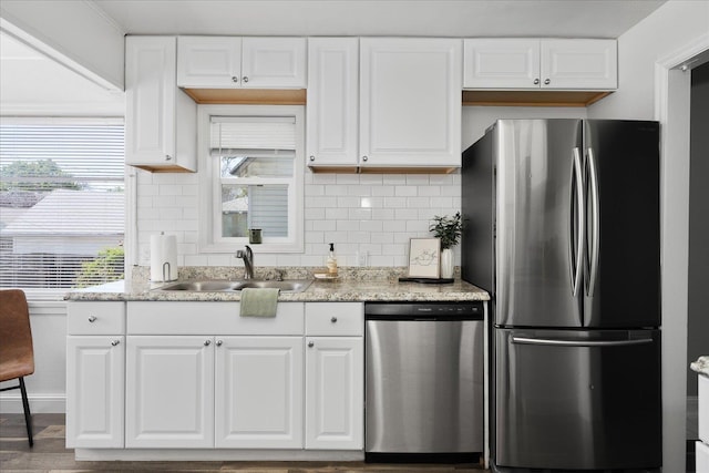 kitchen with a sink, backsplash, stainless steel appliances, and white cabinetry
