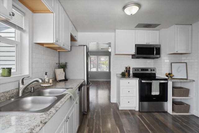 kitchen featuring appliances with stainless steel finishes, dark wood finished floors, a sink, baseboards, and white cabinets