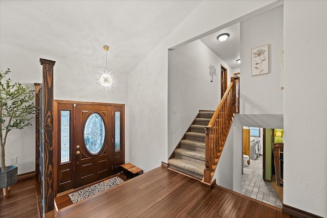 entryway with stairway, a high ceiling, wood finished floors, and a chandelier