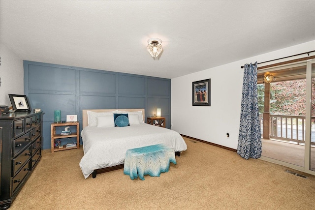 bedroom with visible vents, access to exterior, a decorative wall, and light colored carpet