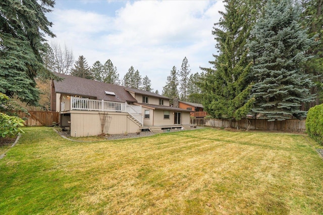 back of house with a fenced backyard, a lawn, a wooden deck, and stairs