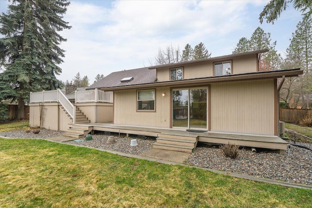back of property with a lawn, fence, stairway, and a deck