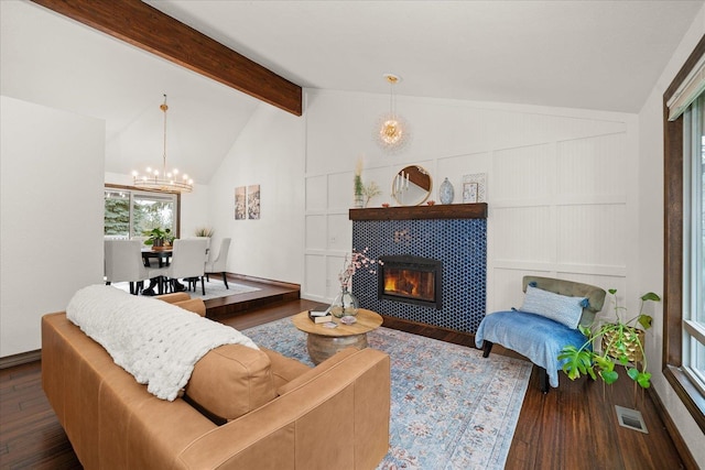 living room with a notable chandelier, lofted ceiling with beams, a tiled fireplace, wood finished floors, and visible vents