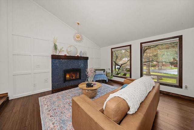 living room featuring baseboards, vaulted ceiling, wood finished floors, and a fireplace