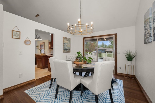 dining area featuring baseboards, a chandelier, wood finished floors, and lofted ceiling