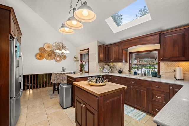 kitchen with stainless steel fridge, a sink, decorative backsplash, a skylight, and butcher block counters
