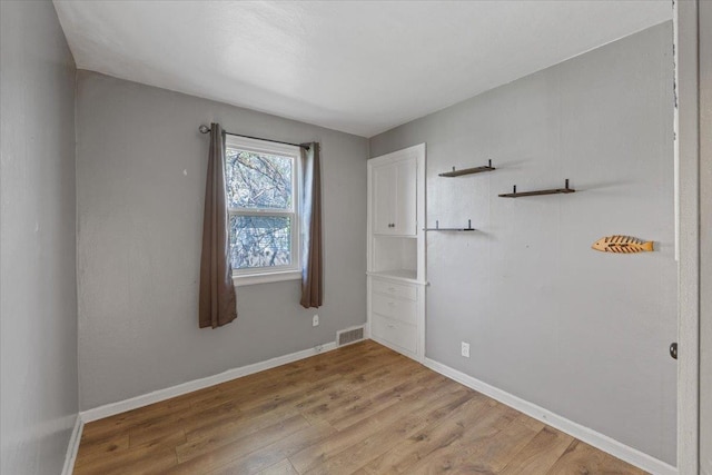 empty room featuring baseboards, visible vents, and light wood-style flooring