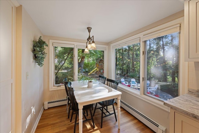 dining room with baseboards, a baseboard radiator, and light wood-style flooring