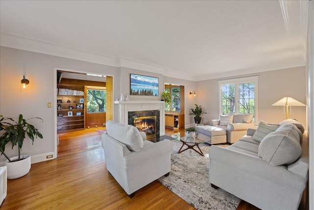living room with crown molding, light wood-style flooring, baseboards, and a fireplace