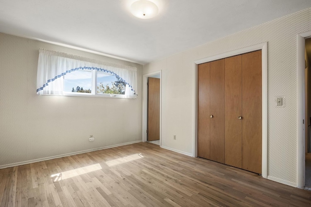 unfurnished bedroom featuring baseboards, a closet, and wood finished floors