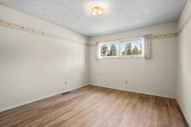 spare room with visible vents, light wood finished floors, and baseboards