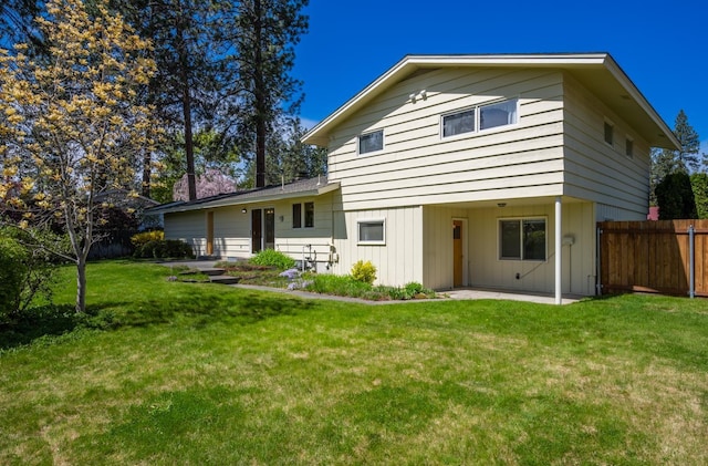 back of house featuring fence, a lawn, and a patio area