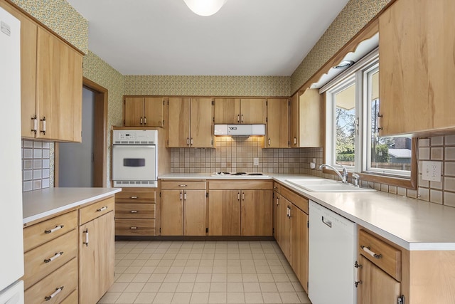 kitchen featuring white appliances, extractor fan, wallpapered walls, light countertops, and a sink