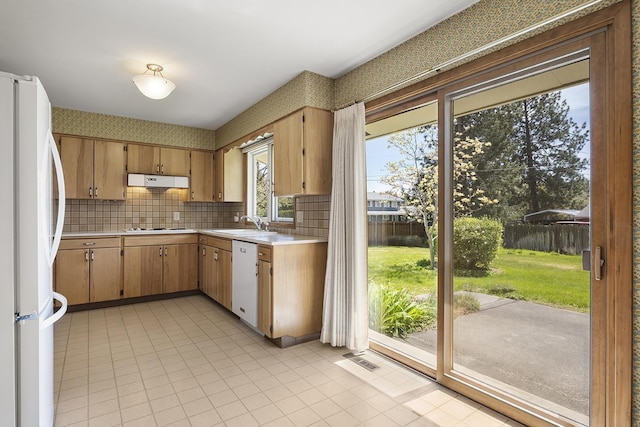 kitchen featuring white appliances, light countertops, decorative backsplash, under cabinet range hood, and visible vents