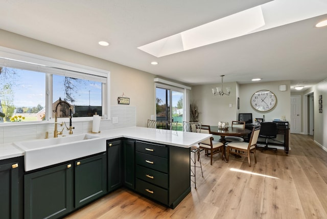 kitchen featuring an inviting chandelier, a peninsula, recessed lighting, a sink, and a skylight