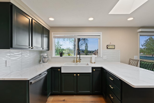 kitchen with a sink, a healthy amount of sunlight, a peninsula, and dishwasher