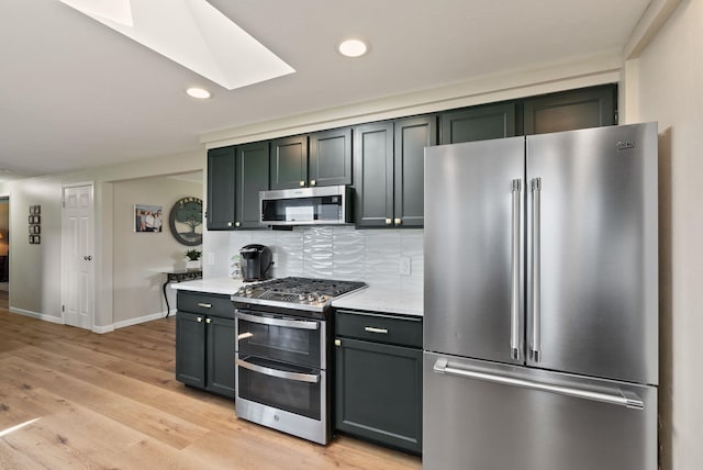 kitchen featuring light countertops, stainless steel appliances, recessed lighting, tasteful backsplash, and a skylight