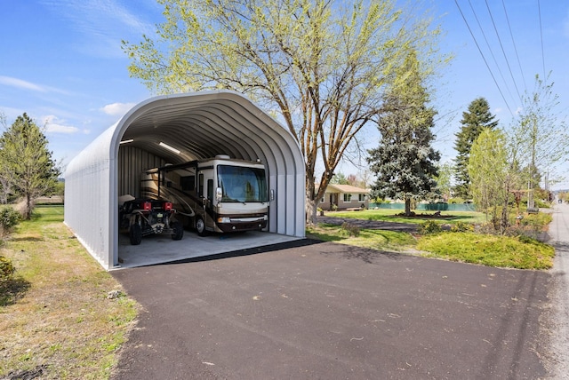 view of parking with a water view, a detached carport, and driveway