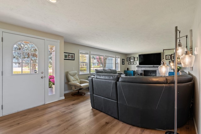 living room with baseboards, a textured ceiling, wood finished floors, and a fireplace