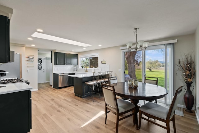 dining area with an inviting chandelier, recessed lighting, a skylight, and light wood-type flooring