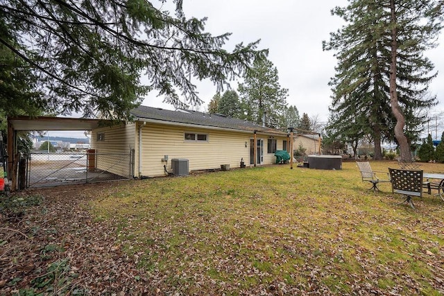 back of property featuring fence, an attached carport, a gate, central air condition unit, and a yard