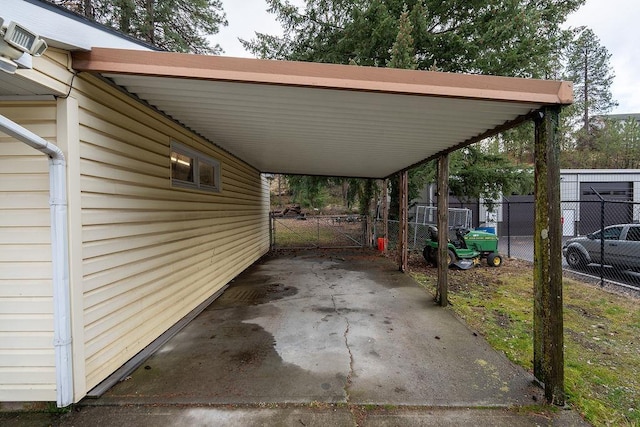 view of car parking featuring a gate, fence, and a carport