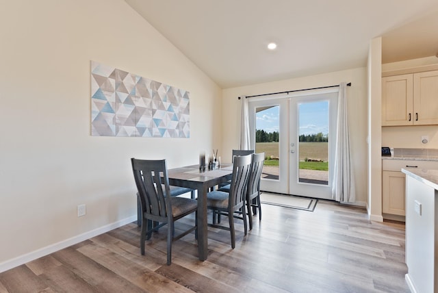 dining space with baseboards, vaulted ceiling, french doors, and light wood-type flooring