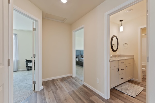 hallway featuring light wood-type flooring, a sink, and baseboards