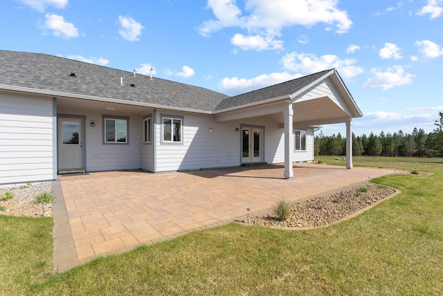 rear view of house featuring french doors, a lawn, a patio area, and roof with shingles