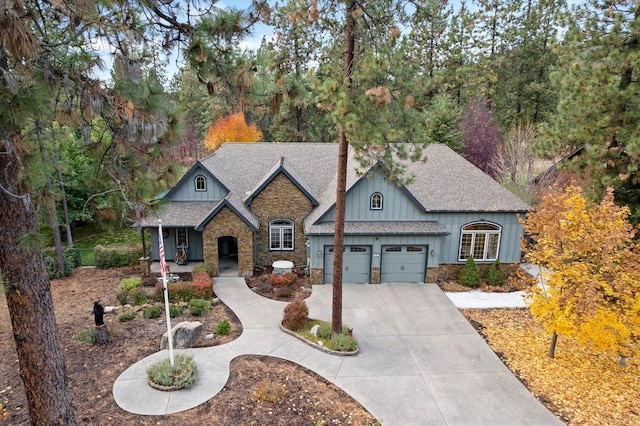 view of front facade with board and batten siding, a porch, a garage, concrete driveway, and a shingled roof