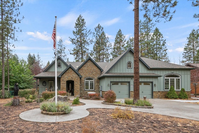 craftsman inspired home featuring stone siding, a shingled roof, board and batten siding, an attached garage, and driveway