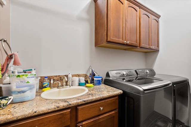 washroom featuring a sink, cabinet space, and independent washer and dryer
