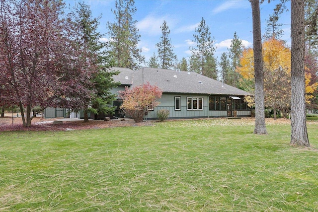 back of property featuring a lawn and roof with shingles
