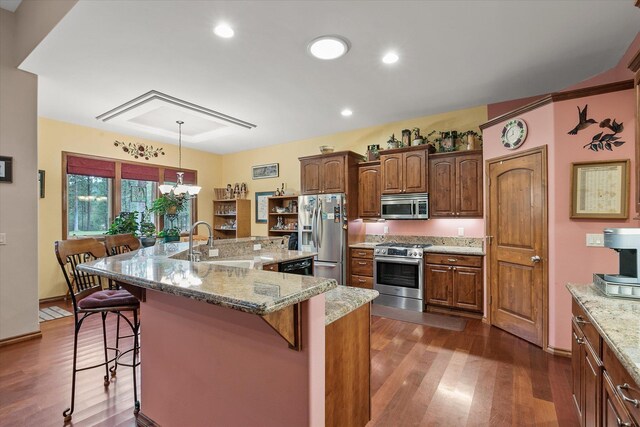 420 Palmer Ln, Chewelah, WA 99109 - kitchen with dark wood-style flooring, light stone counters, a sink, stainless steel appliances, and a kitchen bar