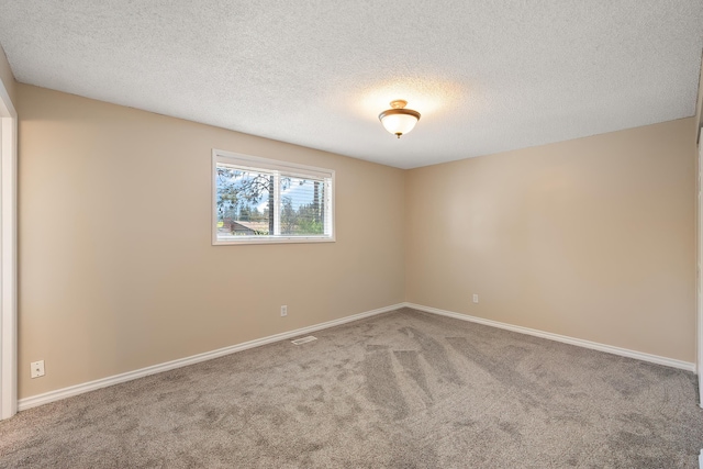 carpeted spare room with a textured ceiling, visible vents, and baseboards