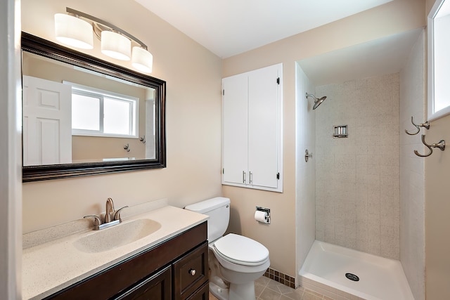 bathroom featuring vanity, tile patterned floors, toilet, and tiled shower