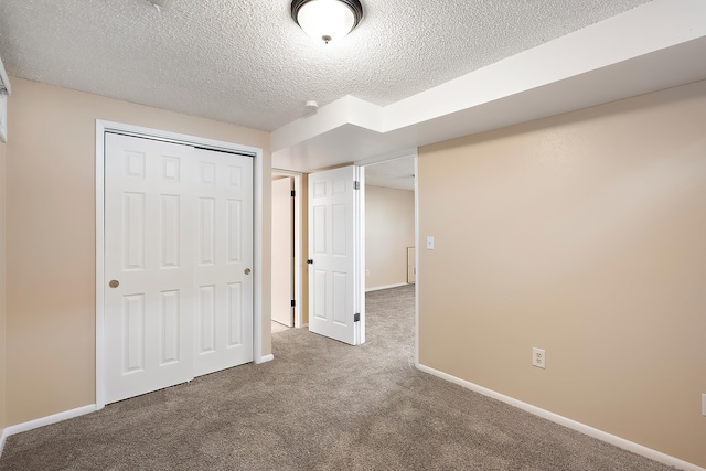 unfurnished bedroom featuring a textured ceiling, baseboards, carpet, and a closet