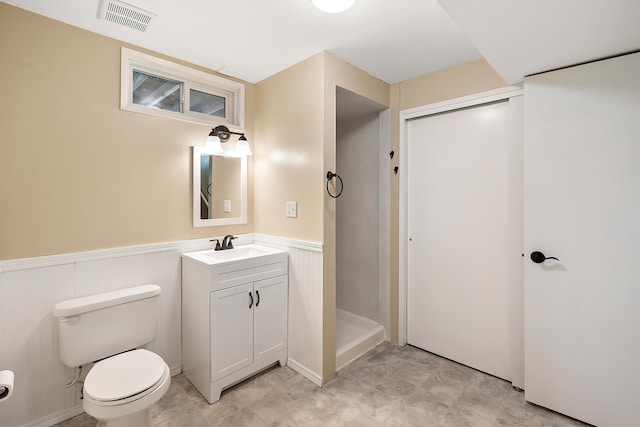 full bath with visible vents, a stall shower, vanity, a wainscoted wall, and toilet