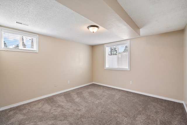 carpeted empty room featuring visible vents, a textured ceiling, and baseboards