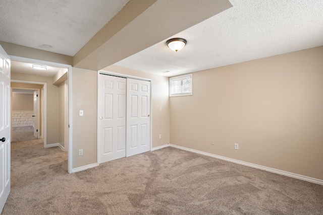 unfurnished bedroom featuring a closet, a textured ceiling, carpet, and baseboards