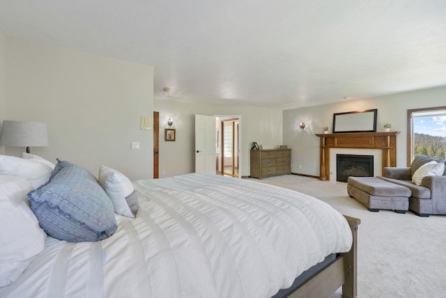 bedroom featuring a glass covered fireplace and light carpet