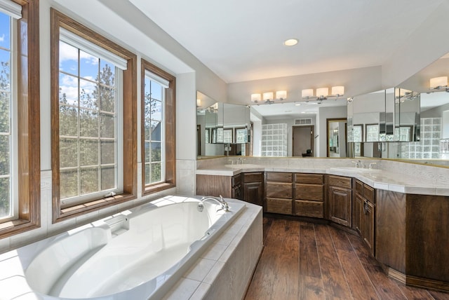 bathroom featuring vanity, wood-type flooring, recessed lighting, visible vents, and a bath
