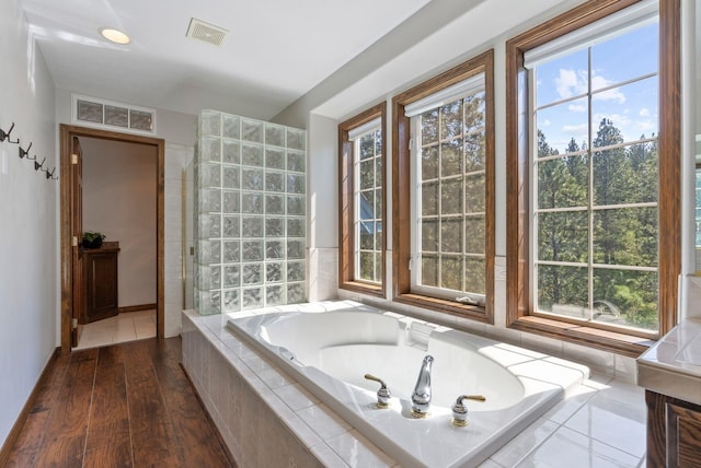 full bath with wood finished floors, a bath, and visible vents