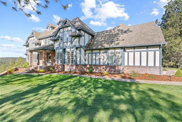 english style home with a porch, a front lawn, and brick siding