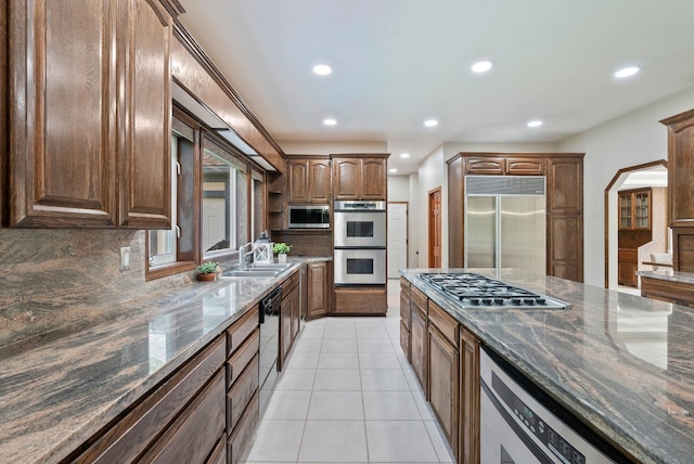kitchen featuring dark stone counters, recessed lighting, appliances with stainless steel finishes, and a sink
