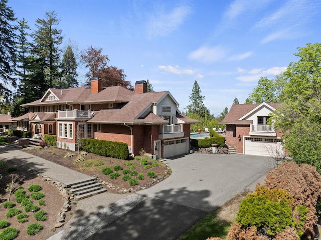 615 E 16th Ave, Spokane, WA 99203 - view of front of house featuring a chimney, a garage, brick siding, a balcony, and aphalt driveway