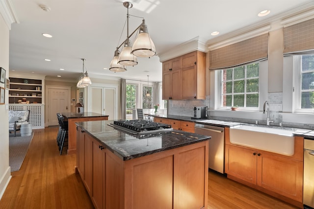 615 E 16th Ave, Spokane, WA 99203 - kitchen featuring light wood finished floors, a center island, a sink, appliances with stainless steel finishes, and tasteful backsplash