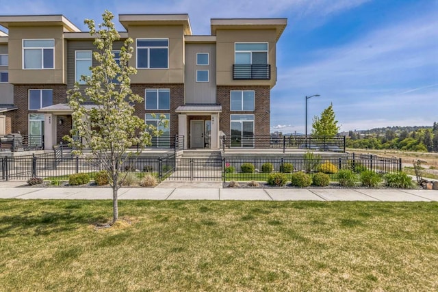 view of front of house with a fenced front yard, a front yard, stucco siding, and brick siding