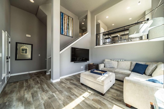 living area featuring baseboards, a high ceiling, stairs, and wood finished floors