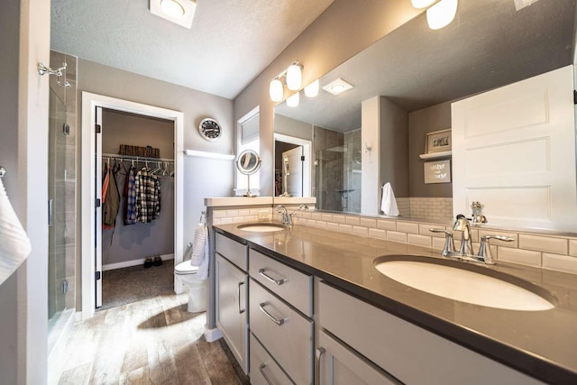 bathroom featuring a sink, double vanity, a stall shower, and wood finished floors